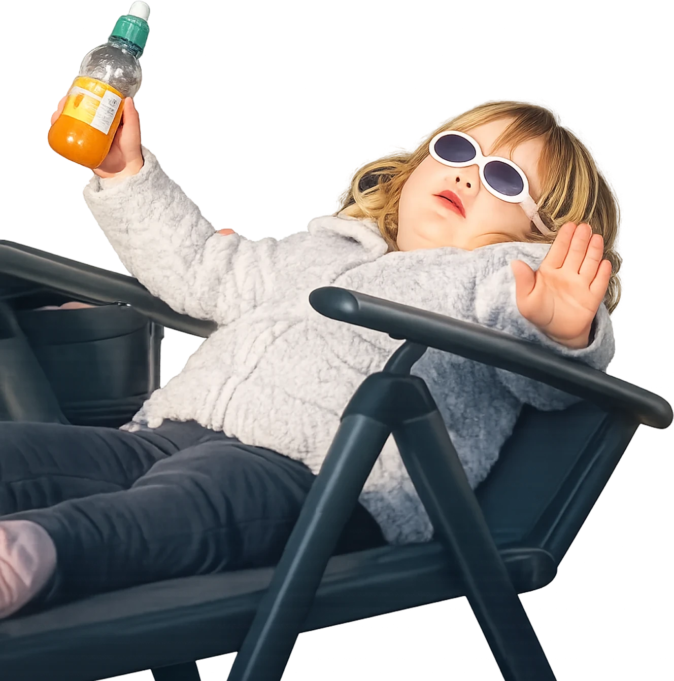 A small girl in sunglasses, reclined in a deck chair, raising a bottle of juice.